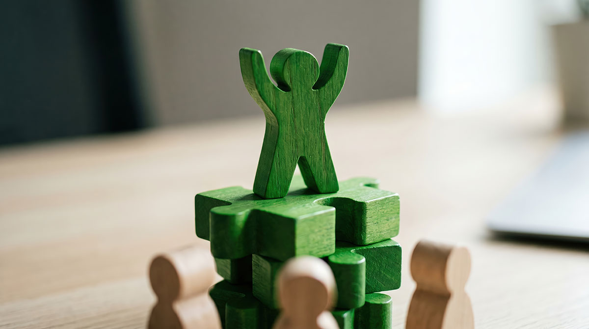 green wooden person figure piece on top of other wooden blocks